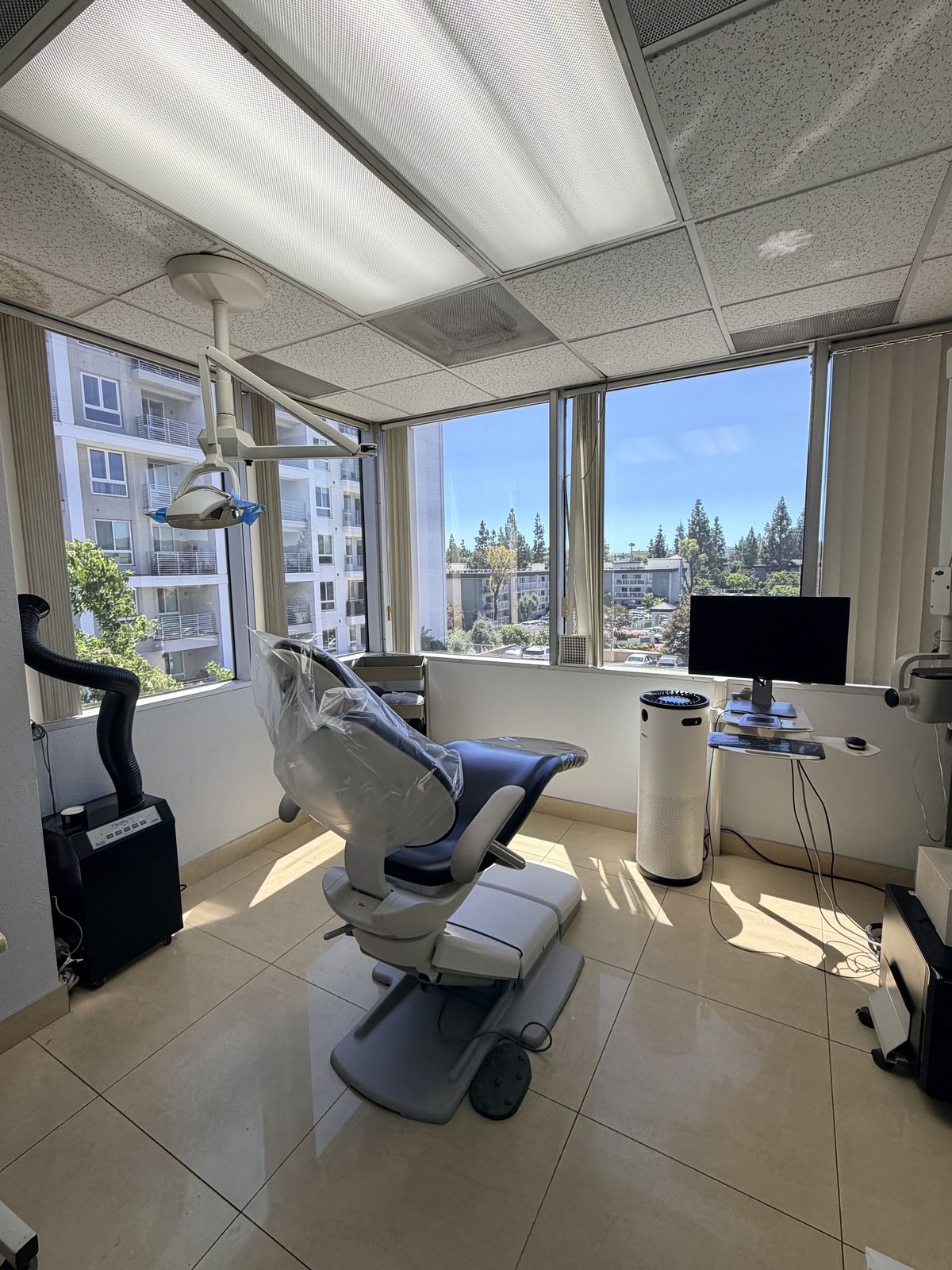 Treatment room with dental chair and corner windows overlooking Woodland Hills