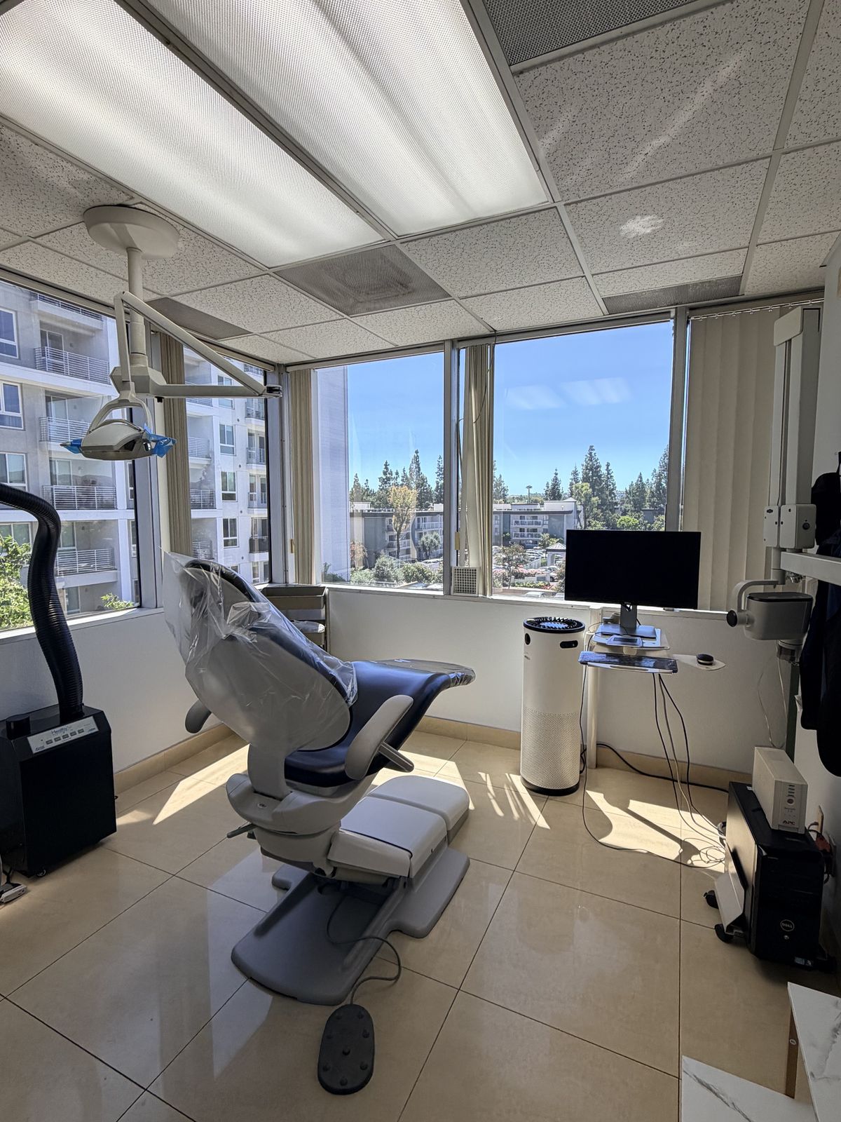 Sunlit treatment suite with dental chair and city view